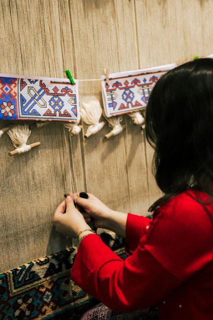 Weaver's hands tying knots at a traditional carpet loom